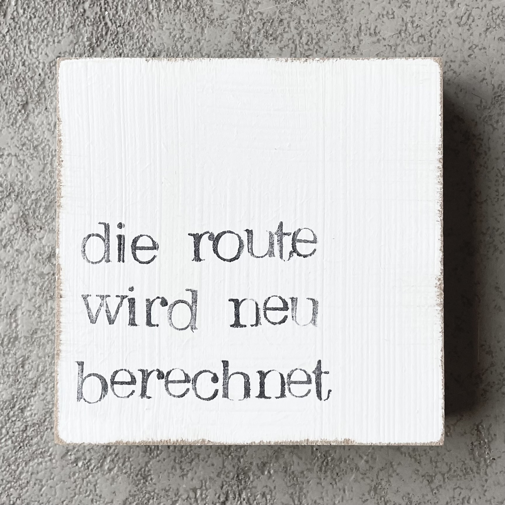 Textplatte "die route wird neu berechnet" 10x10cm, weiß/schwarz